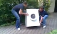 Frau trägt Waschmaschine allein
